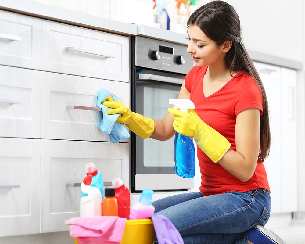 Multi Services cleaner wiping down kitchen cabinets during a home visit